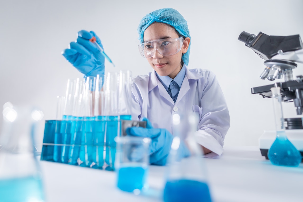 A woman in a lab coat and glasses testing chemicals